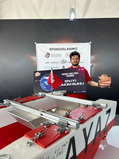 2025 TEKNOFEST En İyi Takım Ruhu ödülü ve kupasıyla Ayaz aracının arkasında duran Ahmet Çağlar
